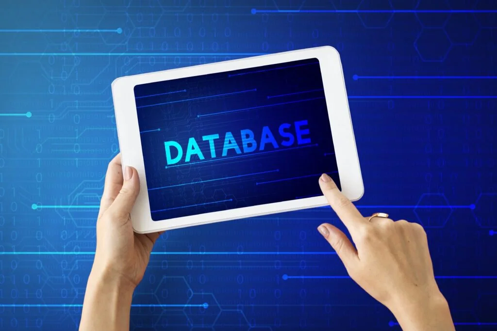  Hands holding a tablet showing database text screen.